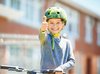 Ein Kind mit Helm und Velo strahlt mit hochgerecktem Daumen in die Kamera