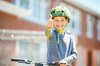 Ein Kind mit Helm und Velo strahlt mit hochgerecktem Daumen in die Kamera