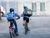Zwei Primarschüler fahren mit ihren Velos davon. Sie tragen beide einen grossen Schulrucksack.