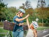 Eine erwachsene Person und ein Schulkind auf dem Velo geben sich ein High five