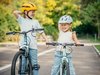 Zwei Mädchen mit lachenden Gesichtern versuchen auf dem Velo die Balance zu halten